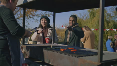 multi ethnic family trying food cooked on grill multi ethnic family trying food cooked on grill adult man takes off ready to eat vegetables and put a portion on plate weekend on local farmers market