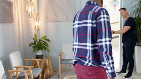 man in plaid shirt entering prosthetic lab, greeted by professional in scrubs