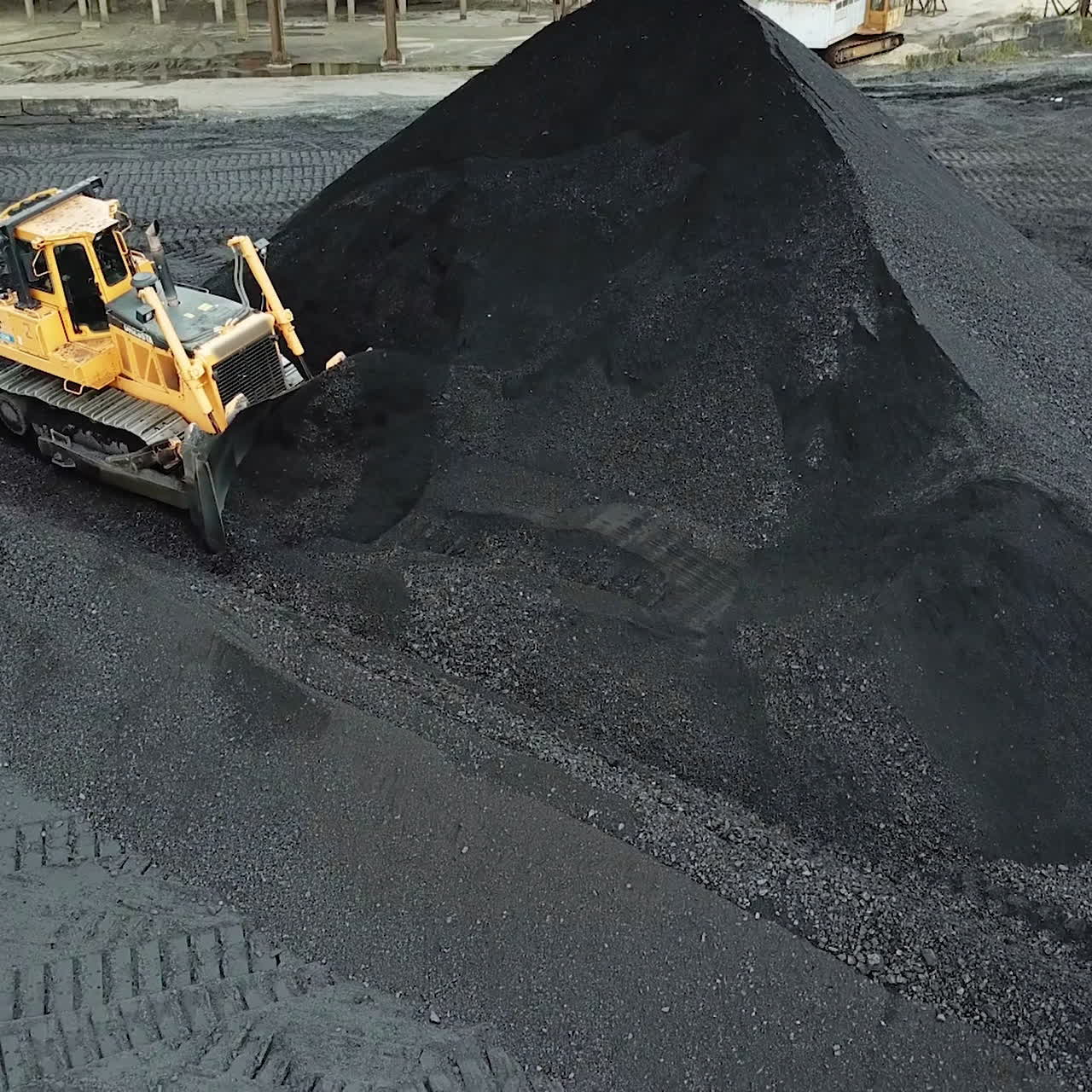 Yellow bulldozer moves the coal. Extractive industry. Aerial view.