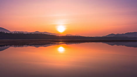 sunrise over a calm lake with mountain reflection
