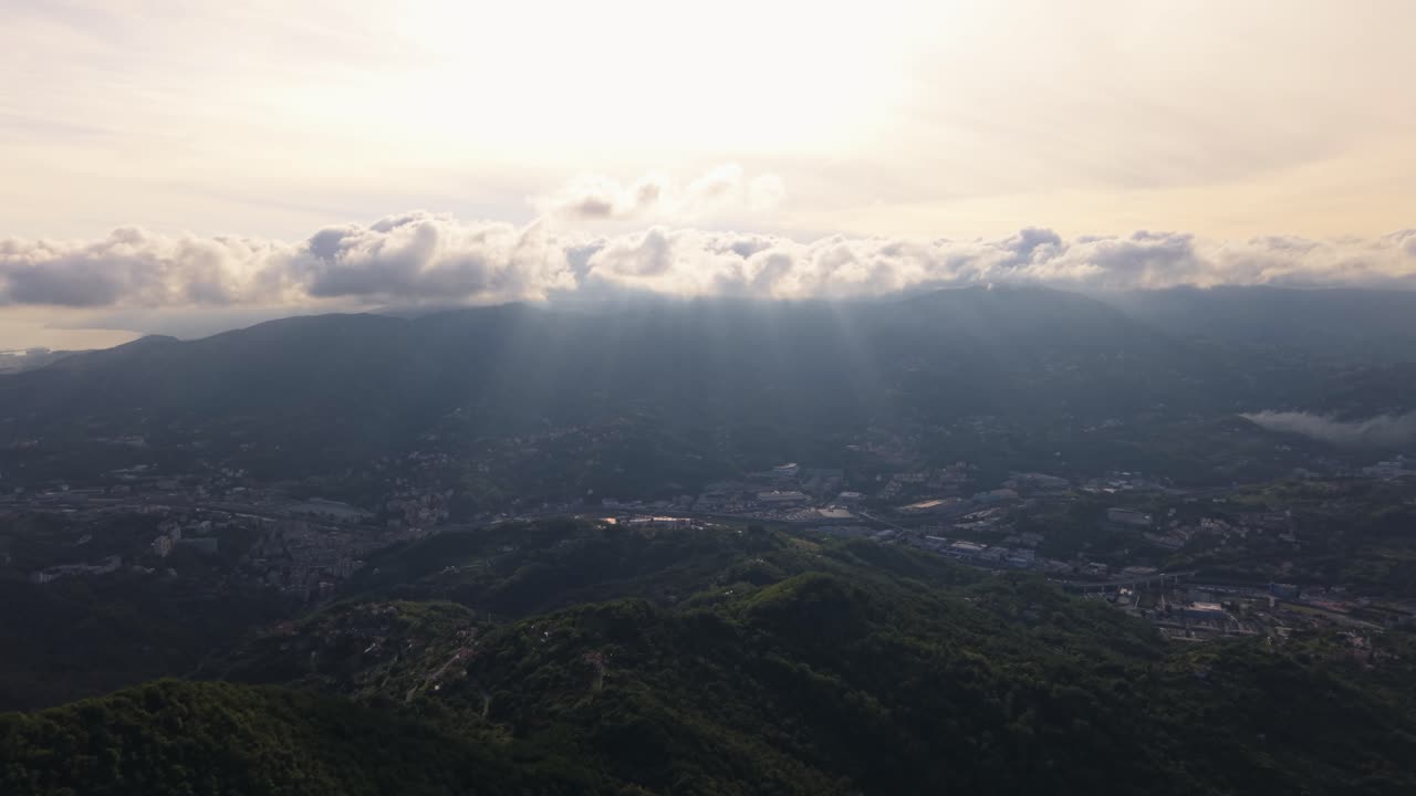 Breathtaking aerial view of Italy's mountains and valley, with sun rays piercing the clouds