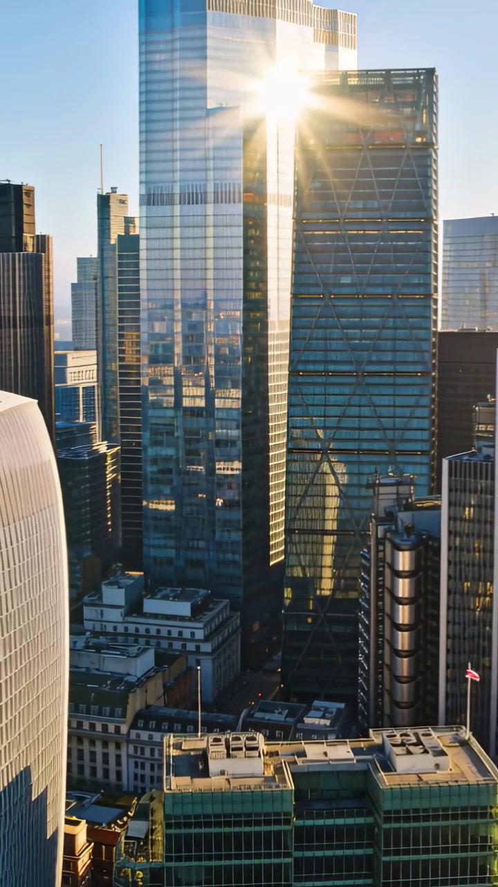 Vídeo vertical: Torres de vidro refletindo o sol, movendo-se para um vão no centro da cidade com reflexo de lente