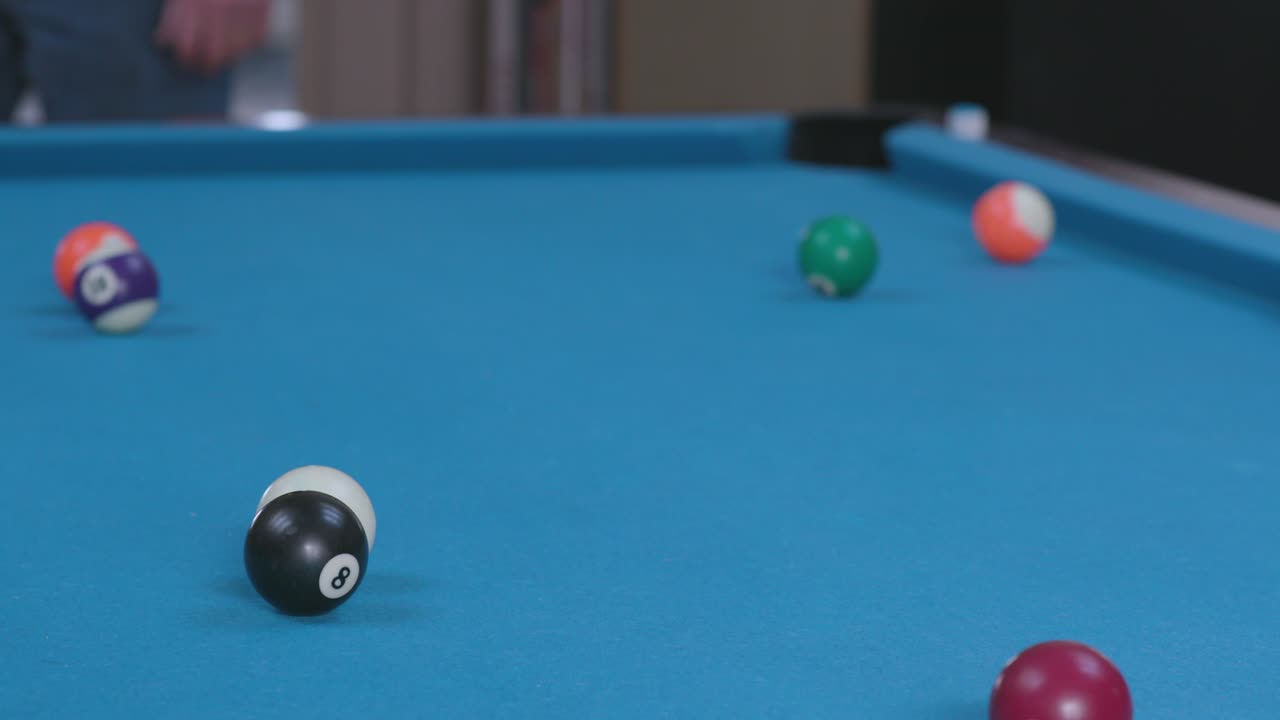 Man Breaking Racked Pool Balls in Eight-Ball Formation on Blue Billiards Table