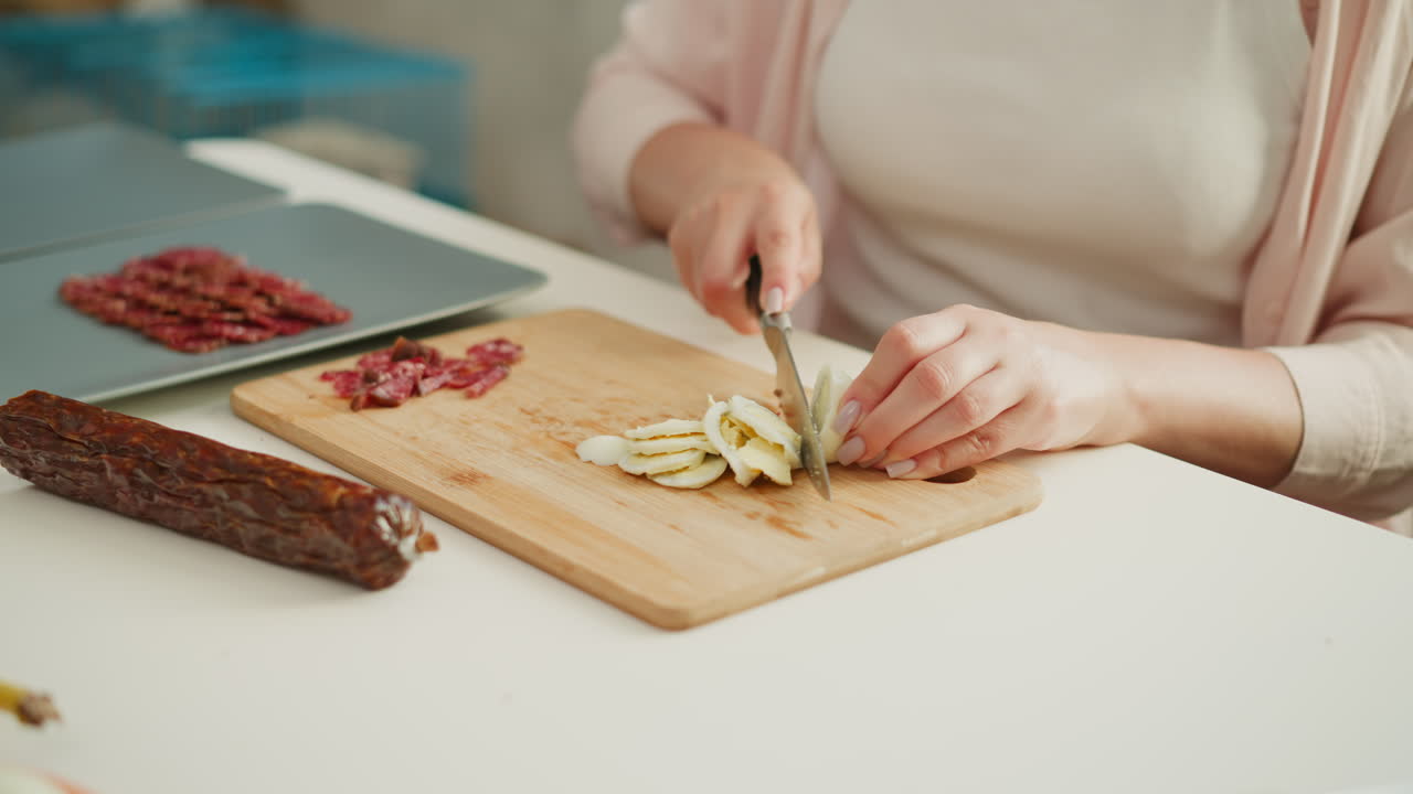 Woman preparing a meal, chopping eggs and sausage