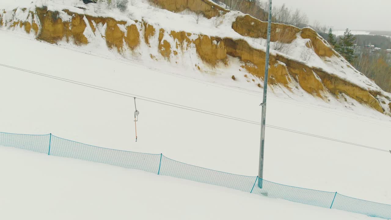 movimiento pasado ascensor t-bar en la pista de la estación de esquí en un día desagradable