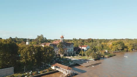 órbita aérea del exclusivo club de remo de tigre junto al río de la plata rodeado de árboles a la hora dorada, buenos aires