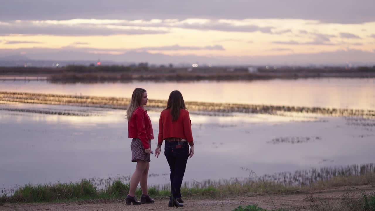 Two women talking at sunset by the lake