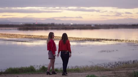 two women talking at sunset by the lake