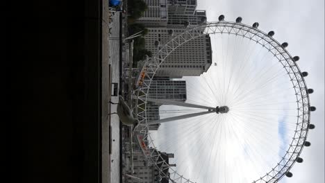 seagulls flying over thames river with london eye in background on a cloudy day in london. vertical
