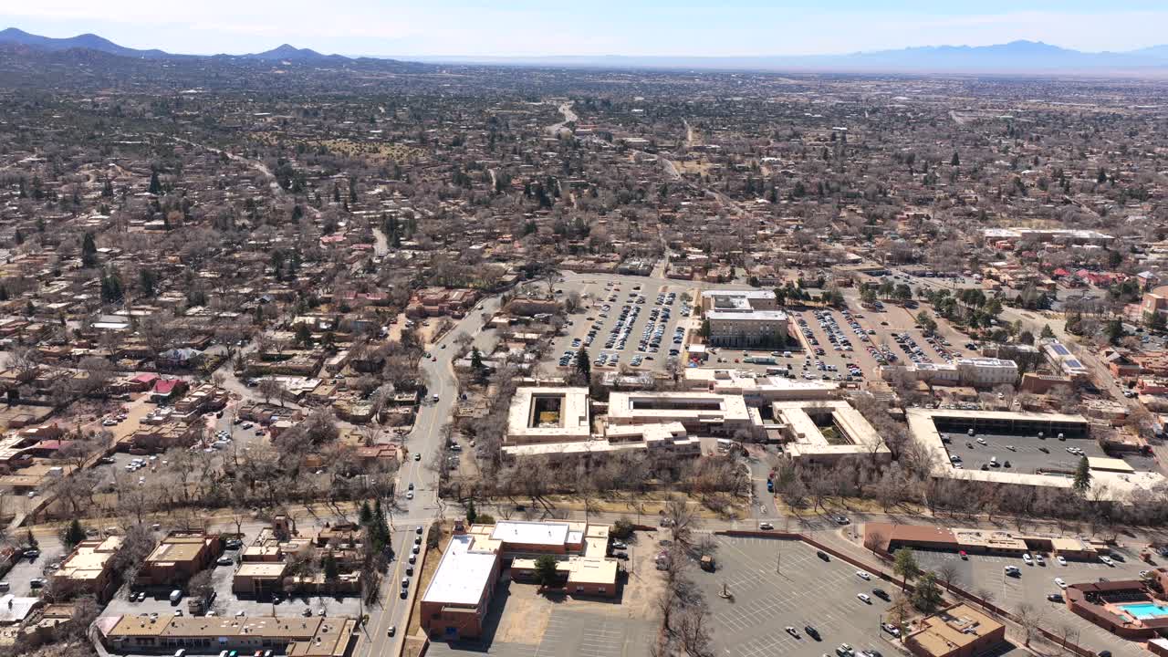 Un'ampia ripresa panoramica cattura lo skyline espansivo di Santa Fe contro uno splendido sfondo montuoso. Questa vista 4K evidenzia la fusione tra il design storico in adobe e lo scenario naturale