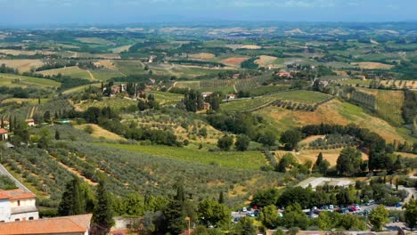 drone flying towards landscape with vineyards and winery on a sunny day in san gimignano, tuscany, italy