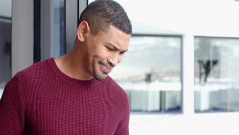 looking out window, man in red sweater contemplating, modern building in background, copy space