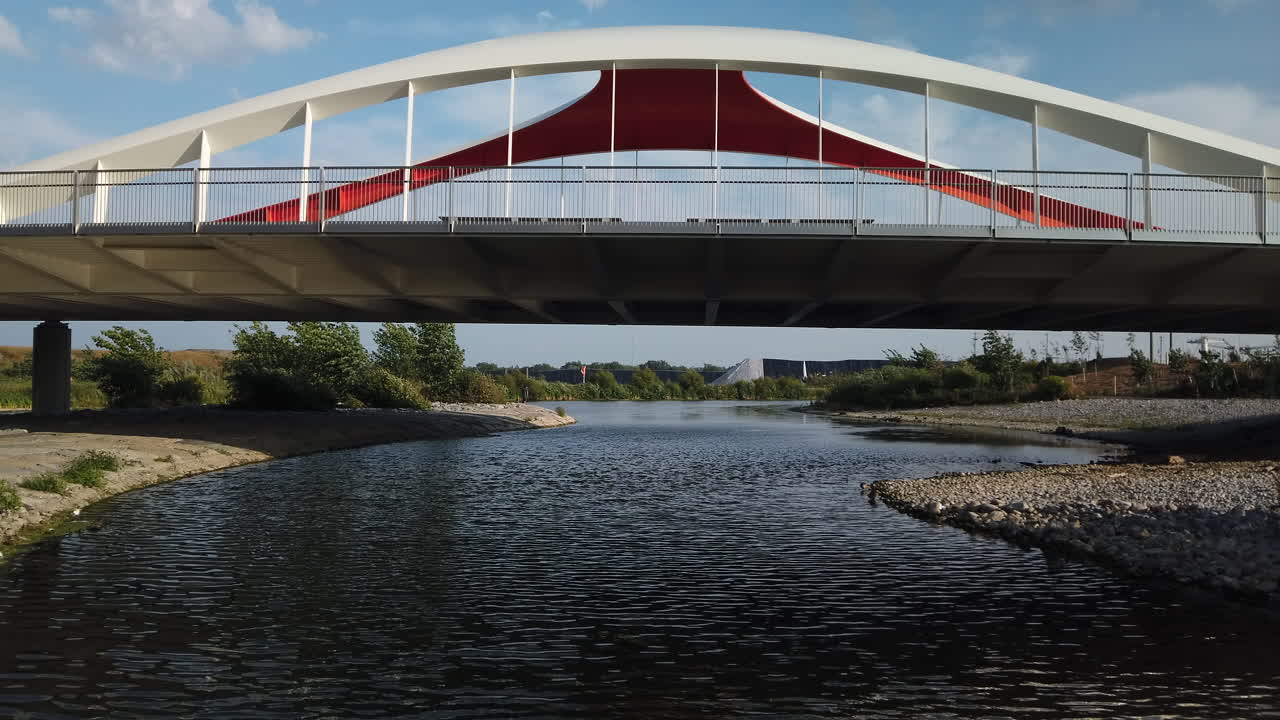 View of Don River flowing under the Commissioners Street bridge in the newly formed Biidaasige Park in Toronto's Port Lands, wide shot