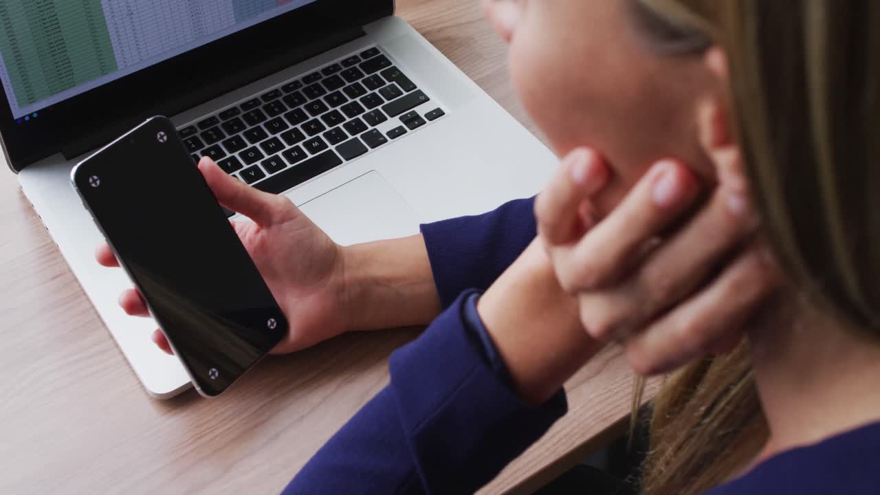 사무실 에서 책상 에 앉아 있는 동안 복사 공간 을 가진 스마트폰 을 사용하는 백인 여성