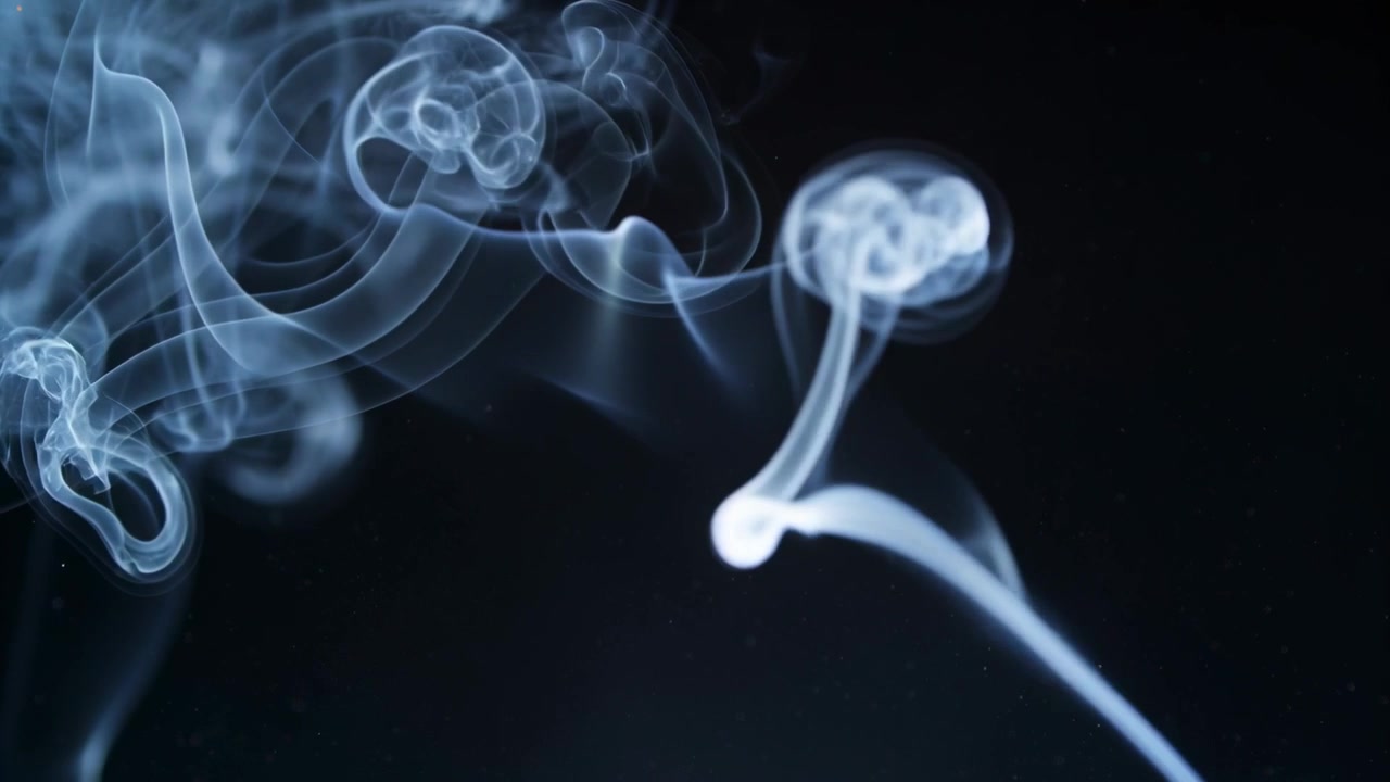 Edge lighting revealing translucent smoke plume curling into loops and bulbs over dark backdrop