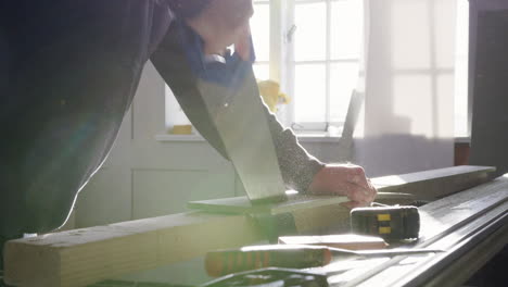 close up of carpenter sawing timber indoors