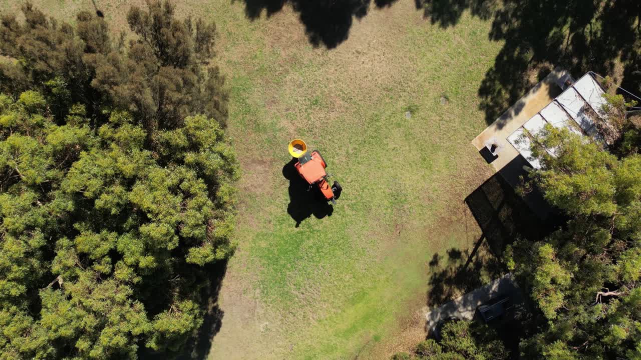 오렌지색 트랙터가 공원에서 씨를 뿌리고 있습니다.