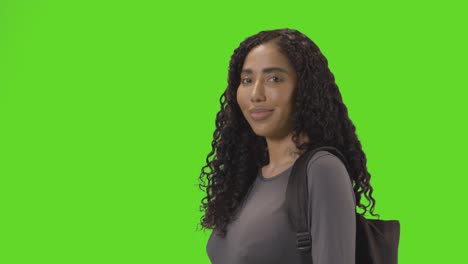 portrait of female college or university student against green screen smiling at camera 1