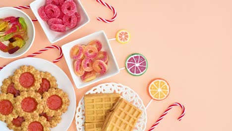 cookies, candies and lollipops move on bright orange background. stop motion flat lay