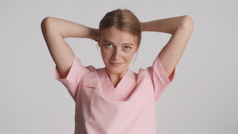 een blanke vrouwelijke dokter die haar haar vastbindt voor de camera.