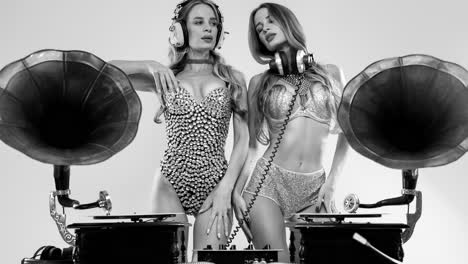 djs gemelas idénticas en trajes plateados brillantes bailando detrás de gramófonos antiguos