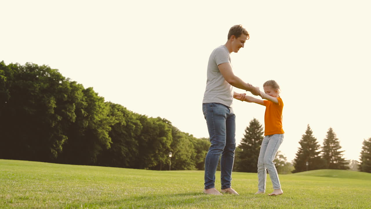 Happy Father Holding Her Little Daughter And Spinning Around On Meadow In The Park 1