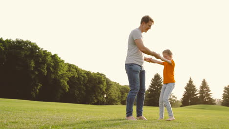 Padre-Feliz-Sosteniendo-A-Su-Pequeña-Hija-Y-Dando-Vueltas-En-El-Prado-En-El-Parque-1