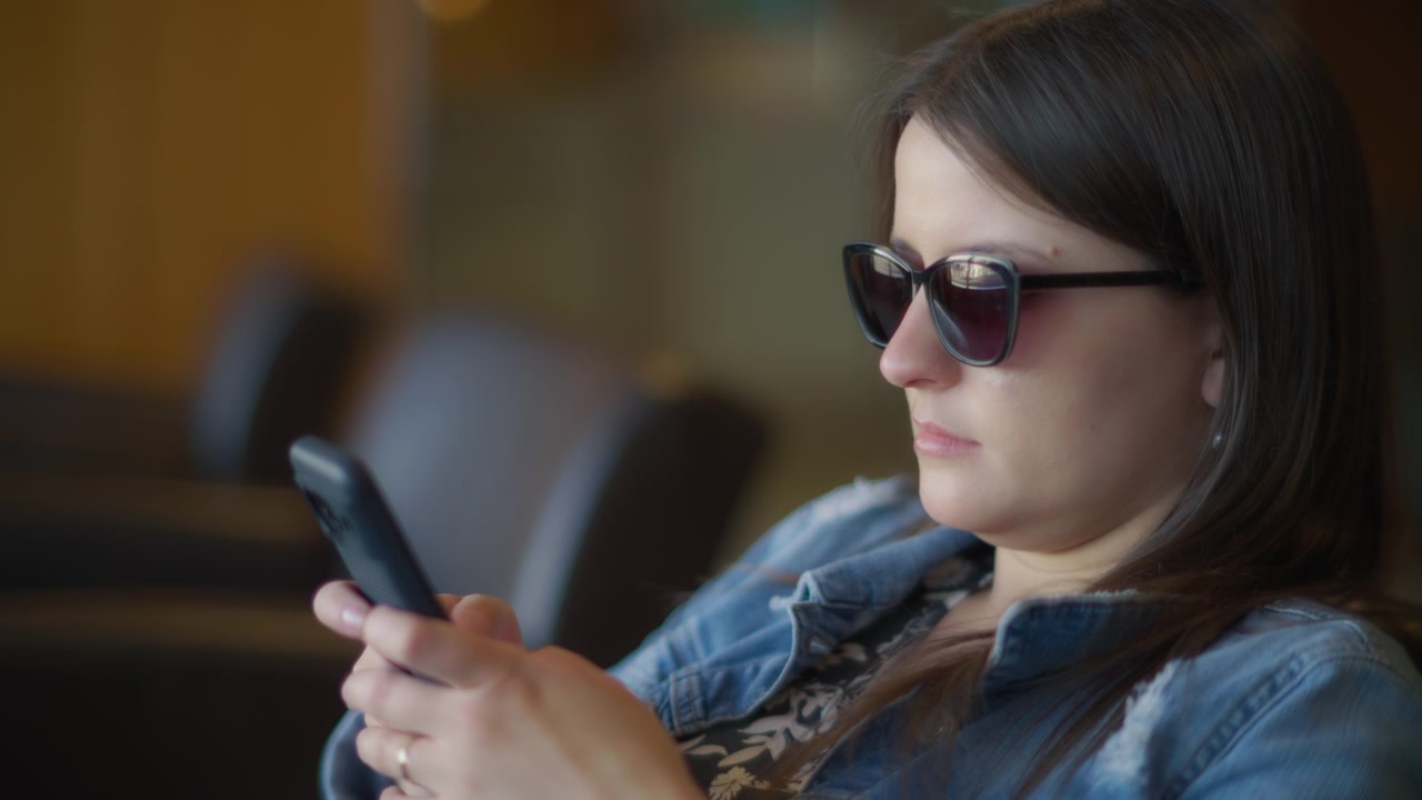Primo piano di una donna che scrive messaggi al telefono nella sala d'attesa del terminal.