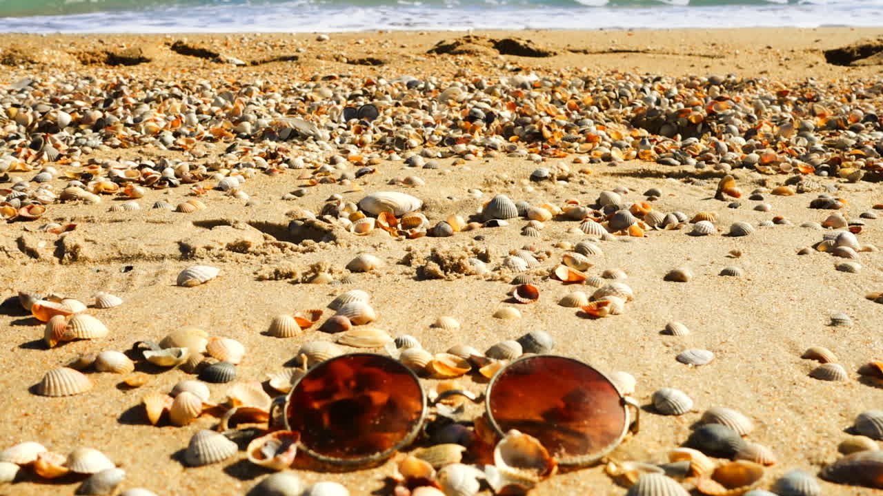 Sunglasses on the sandy beach. Slow motion