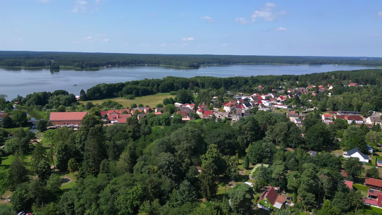 Small village Himmelpfort in Brandenburg Germany, surrounded by lakes and forests on sunny summer day. Unique aerial view flight wide orbit overview drone