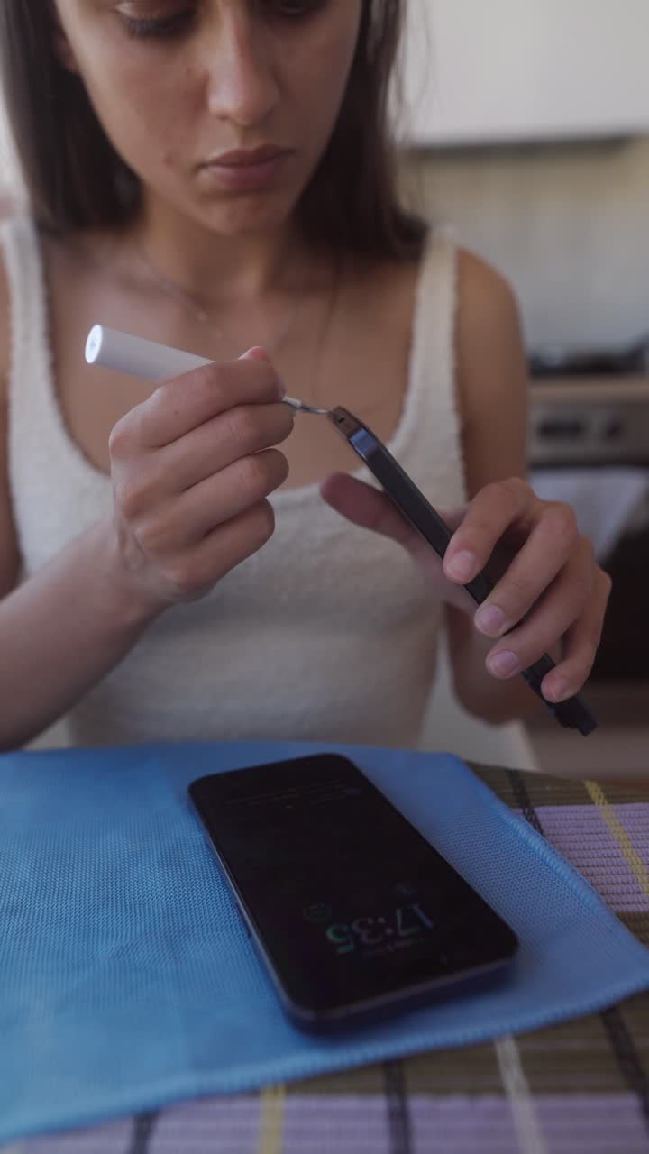 Giovane donna che pulisce la porta di ricarica dello smartphone con un piccolo attrezzo
