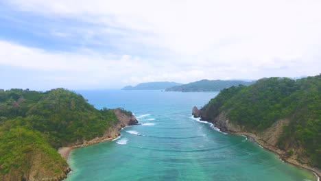 drone flying up over water between two green islands in costa rica's tortuga island archipelago