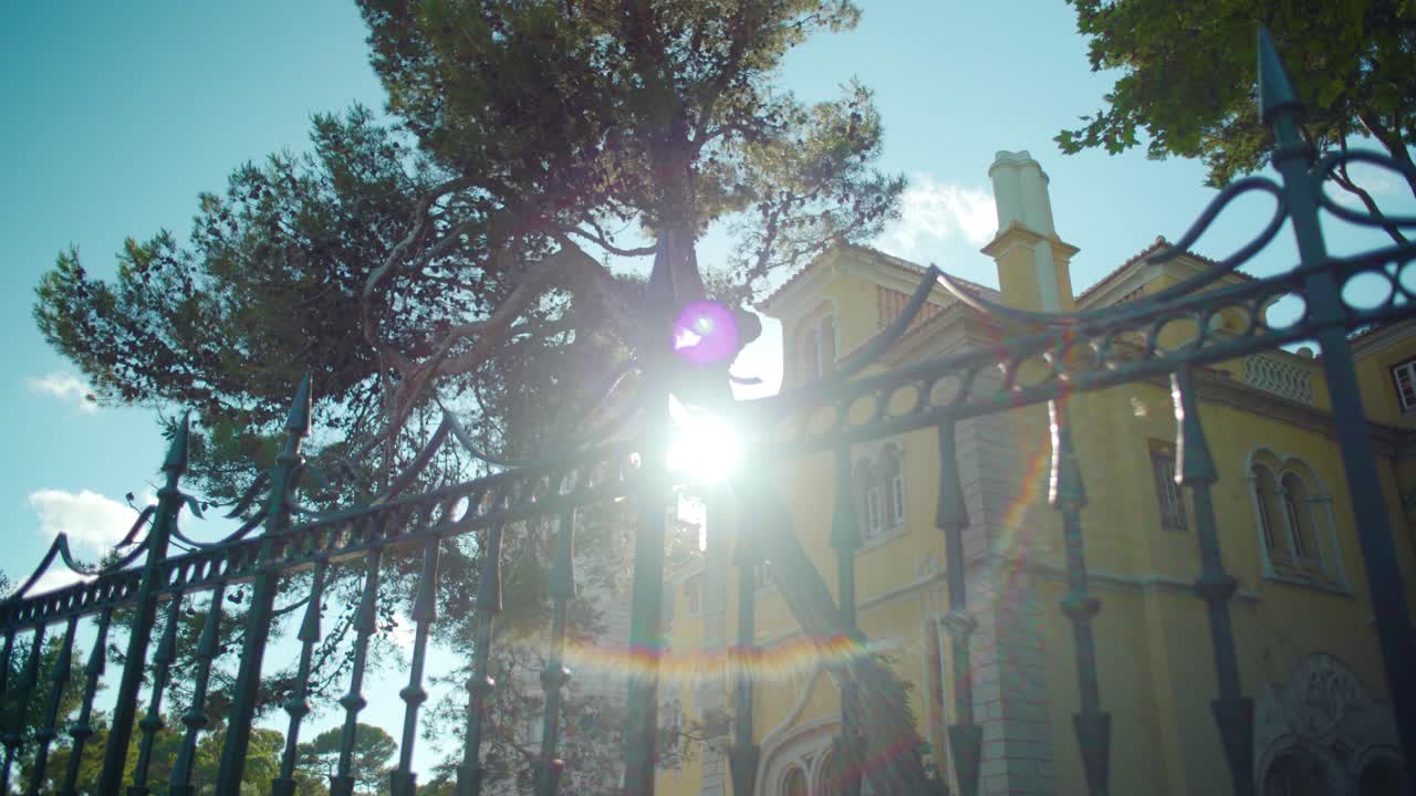 Ancient building facade in camera traveling throw iron fence with sun flares at Cascais Portugal in 4K