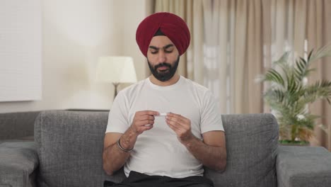 sick sikh indian man using thermometer to check fever