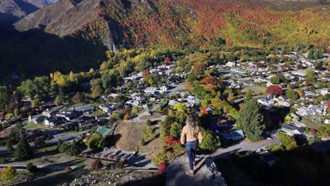 blonde model girl is looking at village covered by colourful trees