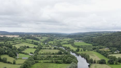 small verdant fields of green farmland beside small countryside river