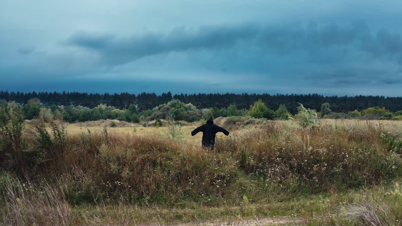 Ghost wandering in nature. Hooded ghostly figure in countryside field
