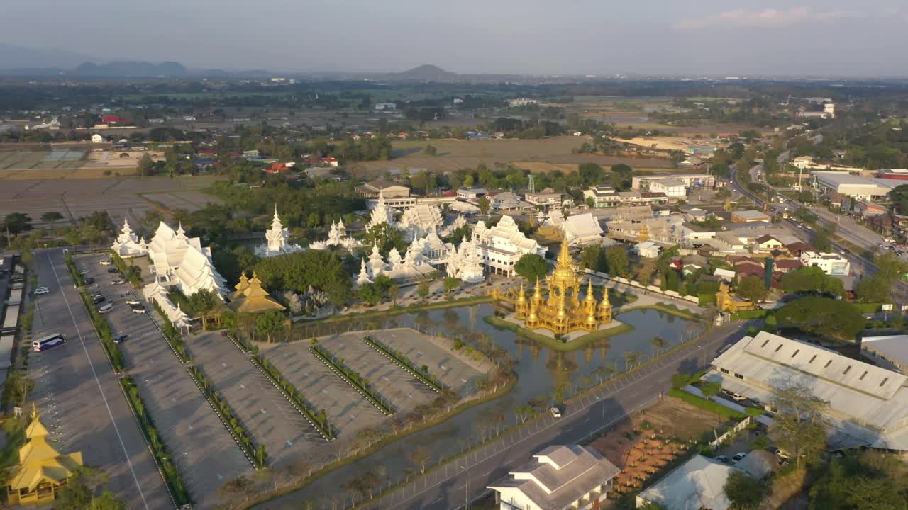 Vista aérea ampla de drone de Wat Rong Khun, o enorme Templo Branco budista e o Templo Dourado, com montanhas e paisagem em Chiang Rai, Tailândia