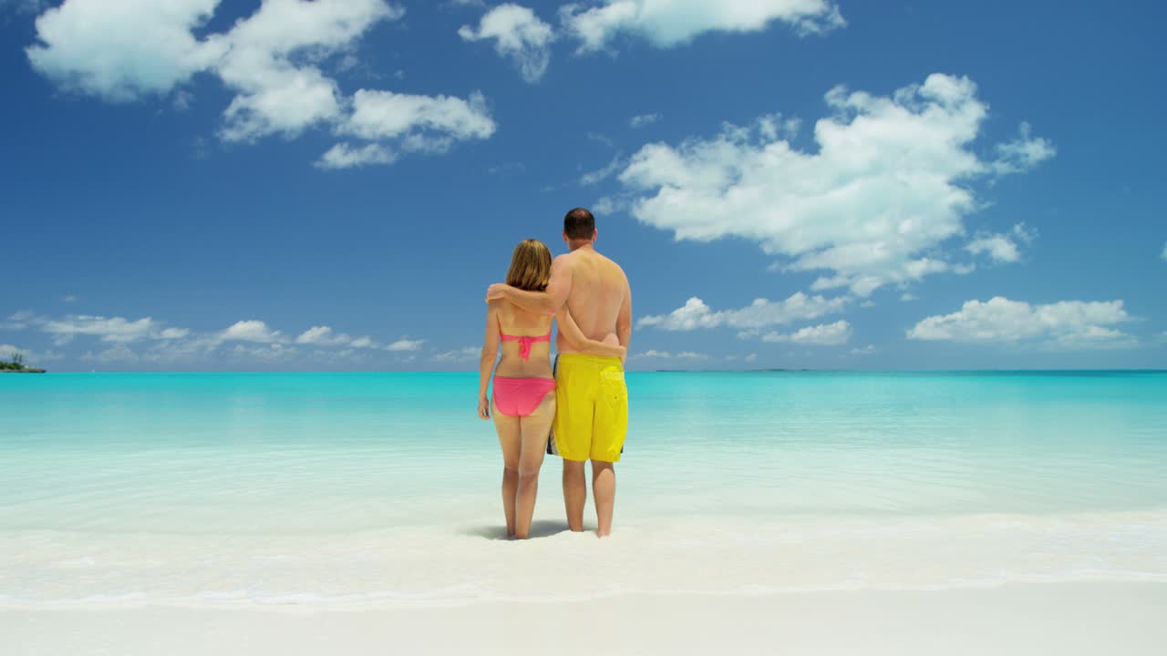 una joven pareja caucásica en trajes de baño en la playa