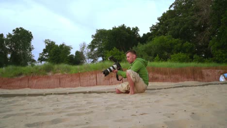 photographer take pictures. man using professional camera on sand beach