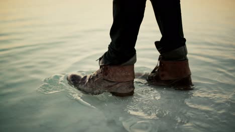 man with leather boots walking into shallows of dead sea