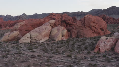 Aerial-revealing-shot-of-the-landscape-behind-the-red-boulders-at-Red-Sandstone-in-Nevada,-USA