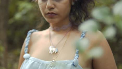 Cinematic-closeup-of-a-fashion-model-wearing-a-necklace-and-a-blue-and-white-dress-in-the-tropical-rainforest-of-Goa-in-India-in-Slow-Motion-Slomo