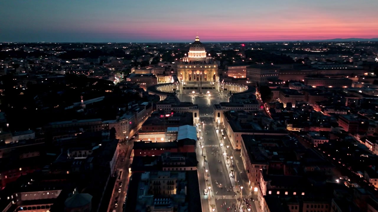 Auto e pedoni si muovono lungo Via della Conciliazione verso Piazza San Pietro e la Basilica di San Pietro sotto un cielo al tramonto colorato.