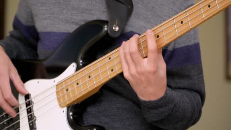 detailed view of a man's hands and fingers on fretboard of an electric bass