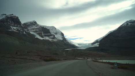 driving on road to athabasca glacier on moody cloudy day, alberta, canada, driver's pov