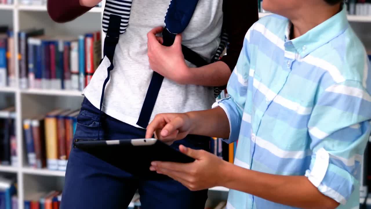 estudiantes felices usando tableta digital en la biblioteca