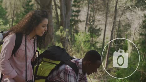 animation of camera icon over diverse couple taking photos with smartphone in nature