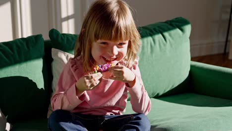 happy girl with colorful treat on sofa