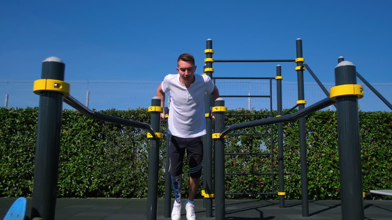 hombre con pierna protésica haciendo inmersiones en barras paralelas